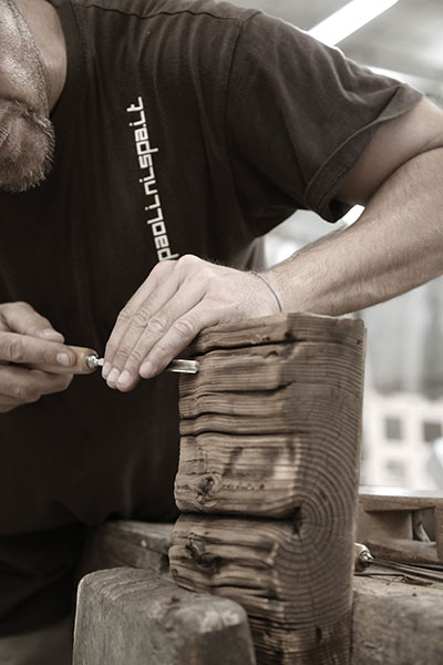 حرفي من باوليني ينحت يدويًا قطعة خشب عمرها قرون ومصدرها شمالي إيطاليا. 