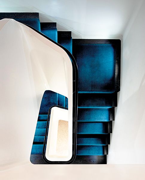 عزز متكأ الدرج من خشب الجوز الداكن وبساط بلون أزرق غامق عنصر التباين مع الدرج الجديد الذي يتخذ شكل منحوتة.