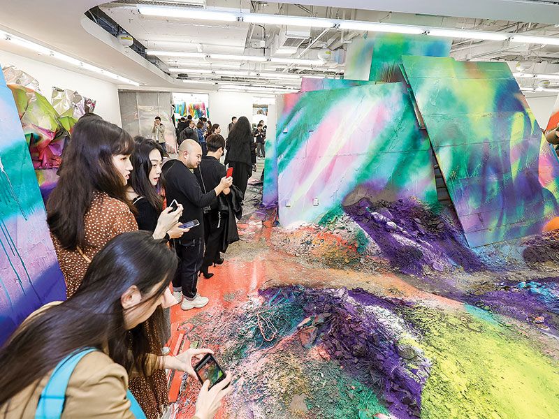 منحوتة Big Pup Head منحوتة Big Pup Head من أعمال الفنان يوشيتومو نارا معروضة في مركز التسوق التجاري K11، زائرون لمركز التسوق التجاريK11 في مدينة شانغهاي وهم يلتقطون صورًا للهيكل المثبت Mumbling Mud من تنفيذ الفنانة كاثارينا غروس.