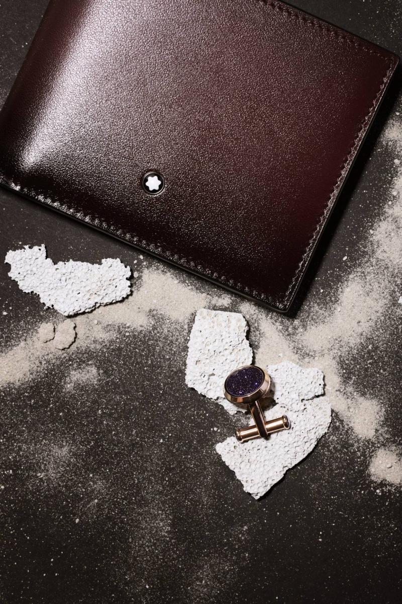 محفظة Meisterstück Wallet 6cc مشغولة من جلد الأبقار، وزرّ للأكمام من مجموعة Meisterstück صيغ من الفولاذ المقاوم للصدأ المصقول بلون الذهب الوردي بتقنية ترسيب البخار الفيزيائي، ورُصّع في مركزه بحجر غولدستون كريستالي باللون الأزرق، كلاهما من مون بلان. 