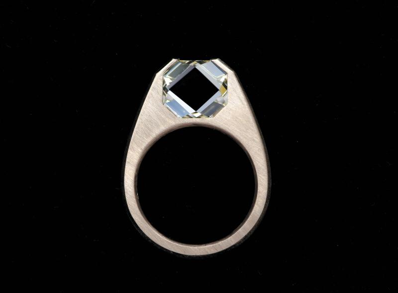 ألماسة مثبّتة بتقنية الضغط والشد، تبدو مثل شظية زجاجية داخل خاتم من الذهب المصقول. 