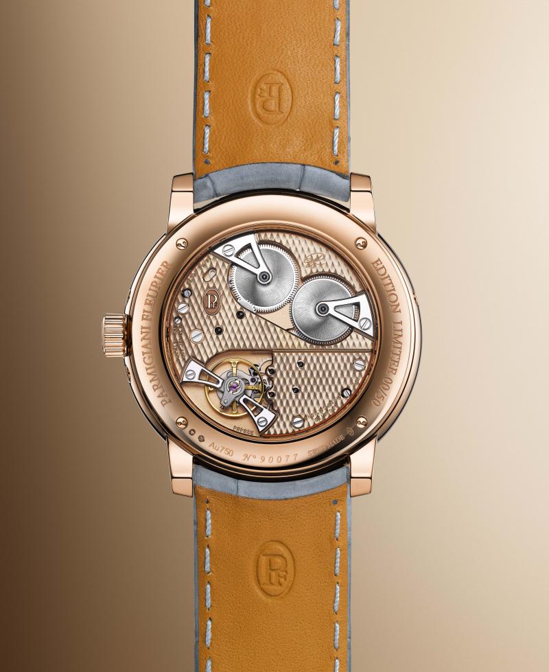 يكشف الغطاء الخلفي لعلبة الساعة عن الجسور الذهبية المزدانة بزخارف كوت دو فلورييه والصفيحة الرئيسة المصقولة بتقنية السفع الرملي.  