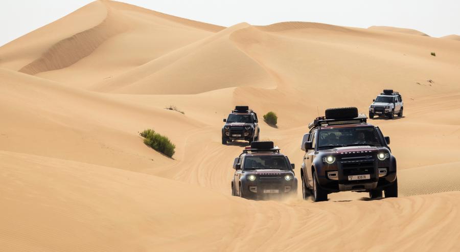 قافلة من سيارات ديفندر 130 تجتاز الكثبان الرملية في صحراء دبي.